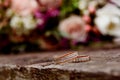 Beautiful wedding rings on a dark wooden background on a background of flowers. Royalty Free Stock Photo