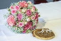 Beautiful wedding rings lie on white surface against the background of a bouquet of flowers and wedding couple Royalty Free Stock Photo