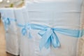 Beautiful wedding set decoration in the restaurant. Blue ribbons on chairs