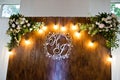 Beautiful wedding set decoration in the restaurant. Rustic wooden photo zone with bulb lamps