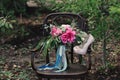 Beautiful wedding shoes with high heels and a bouquet of colorful flowers on a vintage chair on the nature Royalty Free Stock Photo