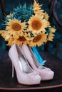 Beautiful wedding shoes with high heels and a bouquet of sunflowers on a vintage chair Royalty Free Stock Photo