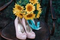 Beautiful wedding shoes with high heels and a bouquet of sunflowers on a vintage chair Royalty Free Stock Photo