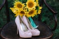 Beautiful wedding shoes with high heels and a bouquet of sunflowers on a vintage chair Royalty Free Stock Photo