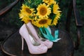 Beautiful wedding shoes with high heels and a bouquet of sunflowers on a vintage chair Royalty Free Stock Photo