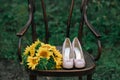 Beautiful wedding shoes with high heels and a bouquet of sunflowers on a vintage chair Royalty Free Stock Photo