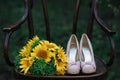 Beautiful wedding shoes with high heels and a bouquet of sunflowers on a vintage chair Royalty Free Stock Photo