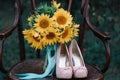 Beautiful wedding shoes with high heels and a bouquet of sunflowers on a vintage chair Royalty Free Stock Photo