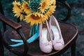 Beautiful wedding shoes with high heels and a bouquet of sunflowers on a vintage chair Royalty Free Stock Photo