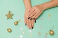 Beautiful well-groomed women`s hands with manicure, on a mint background with gold toys and sequins Royalty Free Stock Photo