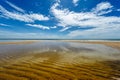 Beautiful white clouds on blue sky over calm sea with sunlight reflection. Midday sky is reflected on water Royalty Free Stock Photo
