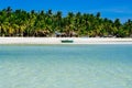 Beautiful white coral sand beach with palms and cottages, turquoise blue ocean Royalty Free Stock Photo