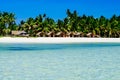 Beautiful white coral sand beach with palms and cottages, turquoise blue ocean Royalty Free Stock Photo