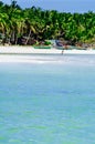 Beautiful white coral sand beach with palms and cottages, turquoise blue ocean Royalty Free Stock Photo