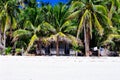 Beautiful white coral sand beach with palms and cottages, turquoise blue ocean Royalty Free Stock Photo