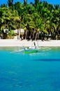 Beautiful white coral sand beach with palms and cottages, turquoise blue ocean Royalty Free Stock Photo