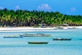 Beautiful white coral sand beach with palms and fishing boats, turquoise blue ocean Royalty Free Stock Photo