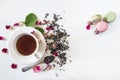 Tea time concept. Beautiful white cup of tea, rose buds, dry tea, green leaves and french macaroons on the white background. Royalty Free Stock Photo