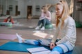 A beautiful white girl sits on a Mat and attentively listens to a lecture on fitness or Pilates.