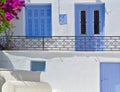 Beautiful white house close up detail with blue window and door, vibrant bougainvillea and balcony with metal railings, Tinos Royalty Free Stock Photo