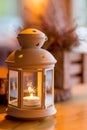 Beautiful white lantern with burning candle inside on wooden table. Toned image. romantic white lantern. Christmas Royalty Free Stock Photo
