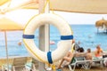 Beautiful white lifebuoy hanged on umbrella at tropical sandy beach. Life saver ring with beautiful blue sea coast on exotic Royalty Free Stock Photo