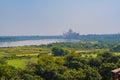 beautiful white marble Taj Mahal is seen from the Red Fort . In the foreground are green fields, a river, blue sky. Royalty Free Stock Photo