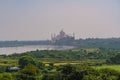 beautiful white marble Taj Mahal is seen from the Red Fort . In the foreground are green fields, a river, blue sky. Royalty Free Stock Photo