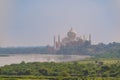 beautiful white marble Taj Mahal is seen from the Red Fort . In the foreground are green fields, a river, blue sky. Royalty Free Stock Photo