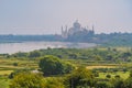 beautiful white marble Taj Mahal is seen from the Red Fort . In the foreground are green fields, a river, blue sky. Royalty Free Stock Photo