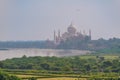 beautiful white marble Taj Mahal is seen from the Red Fort . In the foreground are green fields, a river, blue sky. Royalty Free Stock Photo