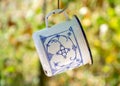Beautiful White Metal Mug With Blue Decorations Hanging On The Pipes In The Garden, Selective Focus