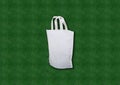 Beautiful White non woven Fabric Shopping Bag with white handle loop on Green Grass Background Royalty Free Stock Photo