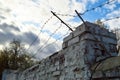 Beautiful white painted brick wall shabby old with cracks in the loft style with seams and barbed wire against the blue Royalty Free Stock Photo