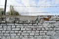 Beautiful white painted brick wall shabby old with cracks in the loft style with seams and barbed wire against the blue sky. Royalty Free Stock Photo