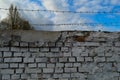 Beautiful white painted brick wall shabby old with cracks in the loft style with seams and barbed wire against the blue sky. Royalty Free Stock Photo