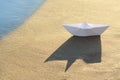 Beautiful white paper boat on sand near sea, space for text Royalty Free Stock Photo