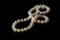 Beautiful white pearls necklace on black background, top view Royalty Free Stock Photo