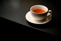 Beautiful white porcelain cup of tea and saucer on black table Royalty Free Stock Photo