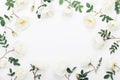 Beautiful white rose flowers and green leaves on table top view. Wedding frame in flat lay styling.