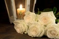 Beautiful white roses and candle on table against black background Royalty Free Stock Photo