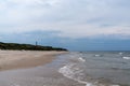 Beautiful white sand beach with a lighthouse in the background high up on grassy sand dunes