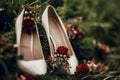 Beautiful white shoes with red bouquets on green grass close up Royalty Free Stock Photo