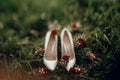 Beautiful white shoes with red bouquets on green grass in the mo Royalty Free Stock Photo