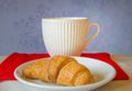 Beautiful white tea Cup with a croissant on red knitted scarf Royalty Free Stock Photo