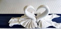 Beautiful White towel folded in heart or two swan shape on bed in bedroom of hotel Royalty Free Stock Photo