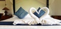 Beautiful white towel folded in two swan shape or heart with blue pillow and wall background Royalty Free Stock Photo