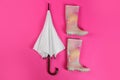 Beautiful white umbrella and colorful rubber boots on pink background, flat lay Royalty Free Stock Photo