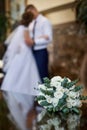 Beautiful white wedding bridal bouquet and on the background kiss the bride and groom Royalty Free Stock Photo
