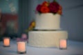 Beautiful white wedding cake with real flowers surrounded by candles Royalty Free Stock Photo